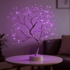 Veilleuse arbre lumineux bonsaï en lumière rose violacé, posée sur une table basse dans un salon
